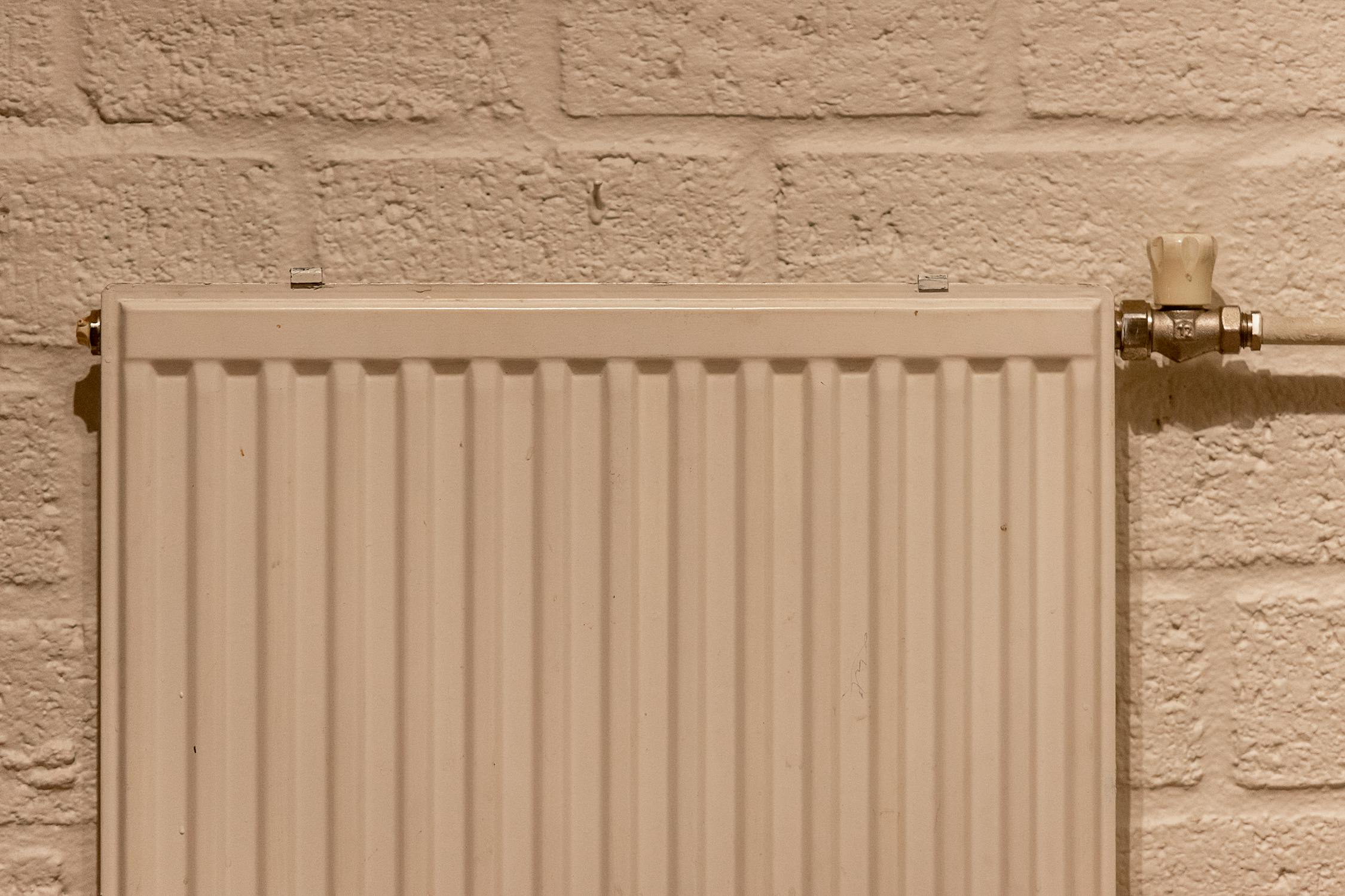 White wall-mounted heating panel on an exposed brick wall