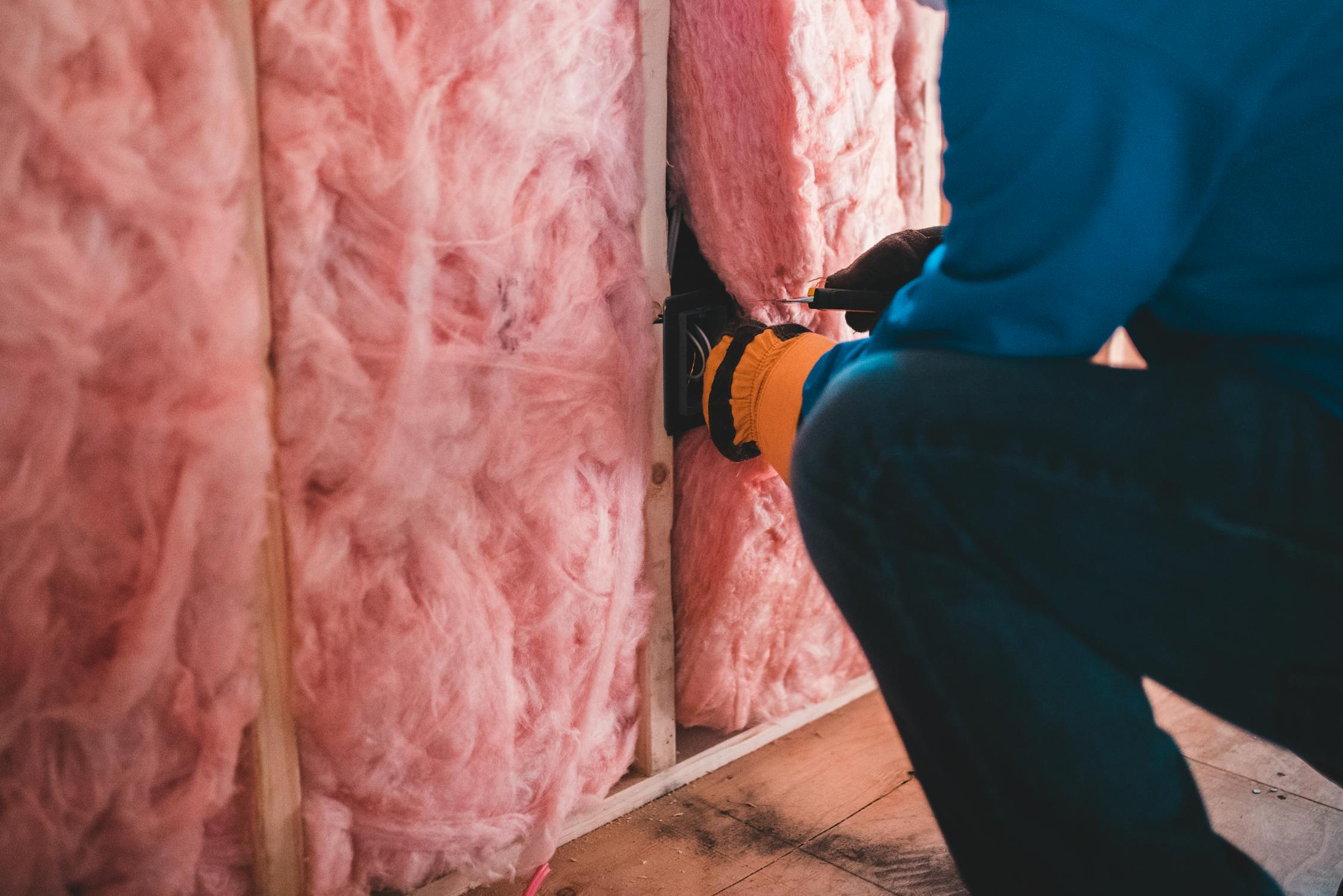 Worker fitting insulation material into a wall cavity