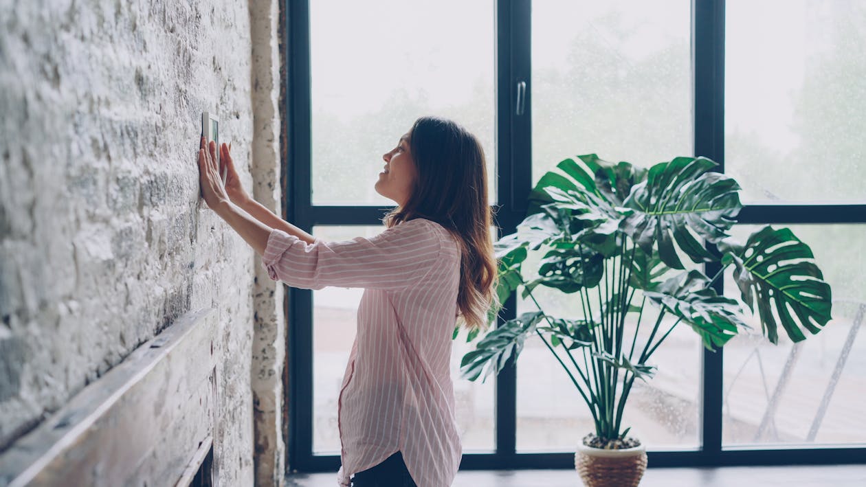 Woman adjusting a smart thermostat in a modern home